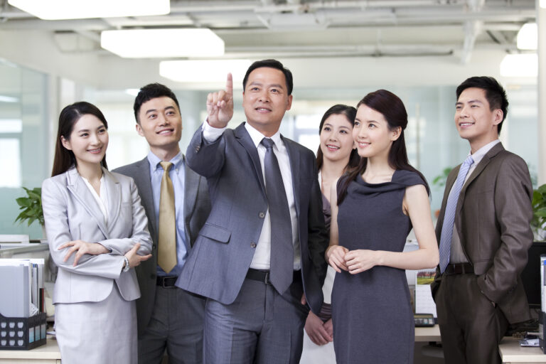 Happy Chinese businesspeople pressing on a virtual screen