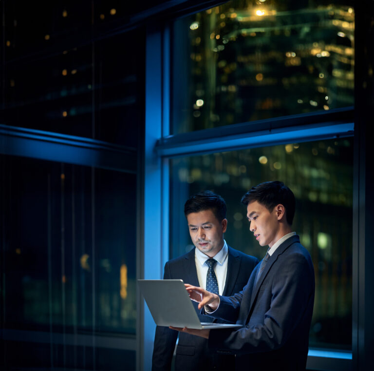 Two,Asian,Corporate,Executives,Standing,By,The,Window,In,Office