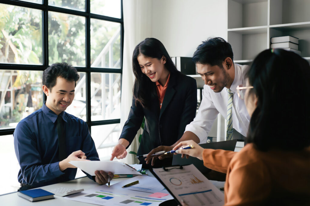 Two women and two men in a business meeting, Diverse business people laughing during a meeting, Business colleagues discussing strategy in the office, Business people negotiating at boardroom.
