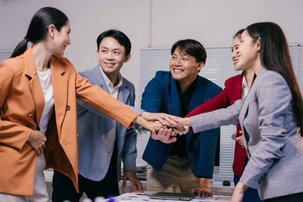 Asian,Businesspeople,Joining,Hands,Together,,Celebrating,Success,And,Teamwork,In