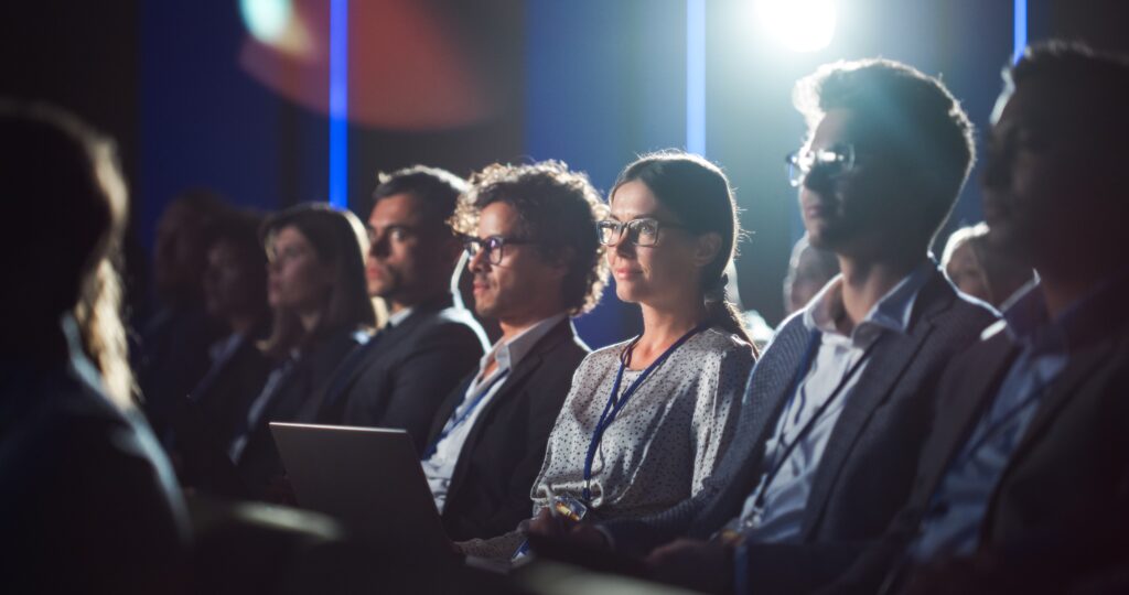 a crowd of business experts listening to a conference