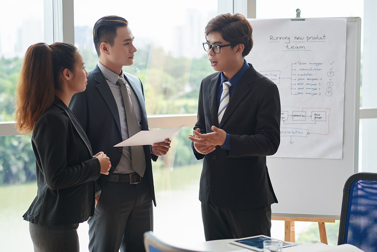 Business professionals discussing strategy and leadership decisions during a collaborative meeting, representing executive learning and career growth through an EMBA.