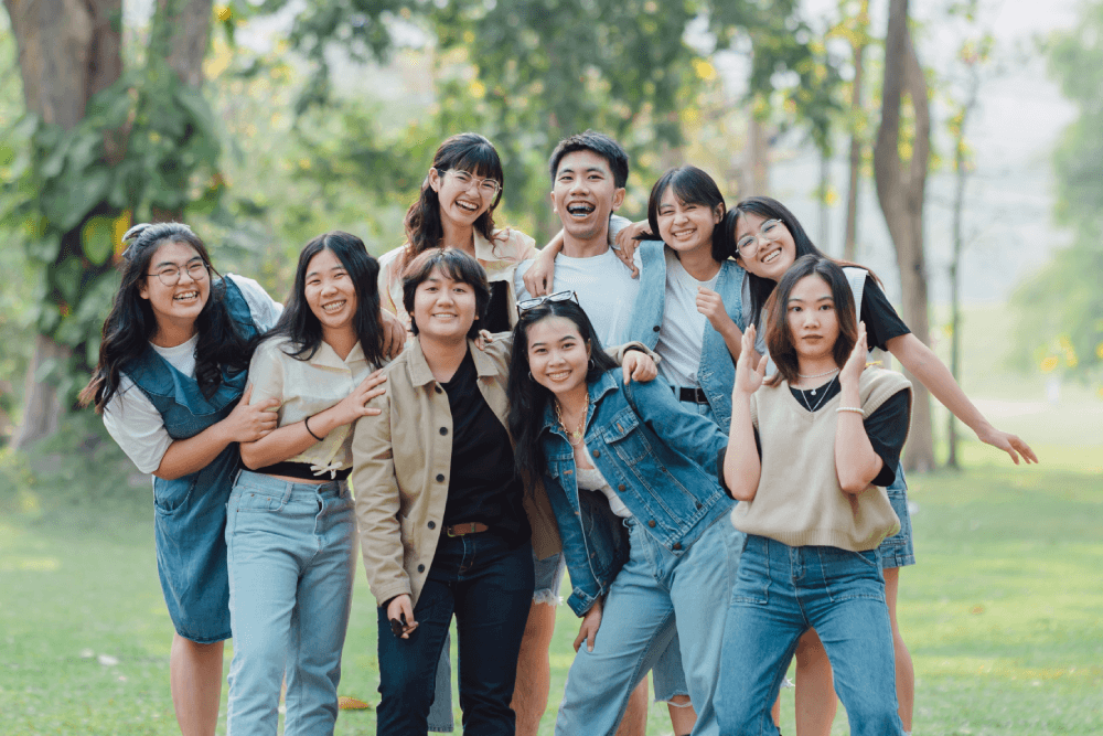 A group of diverse students smiling together in a park.